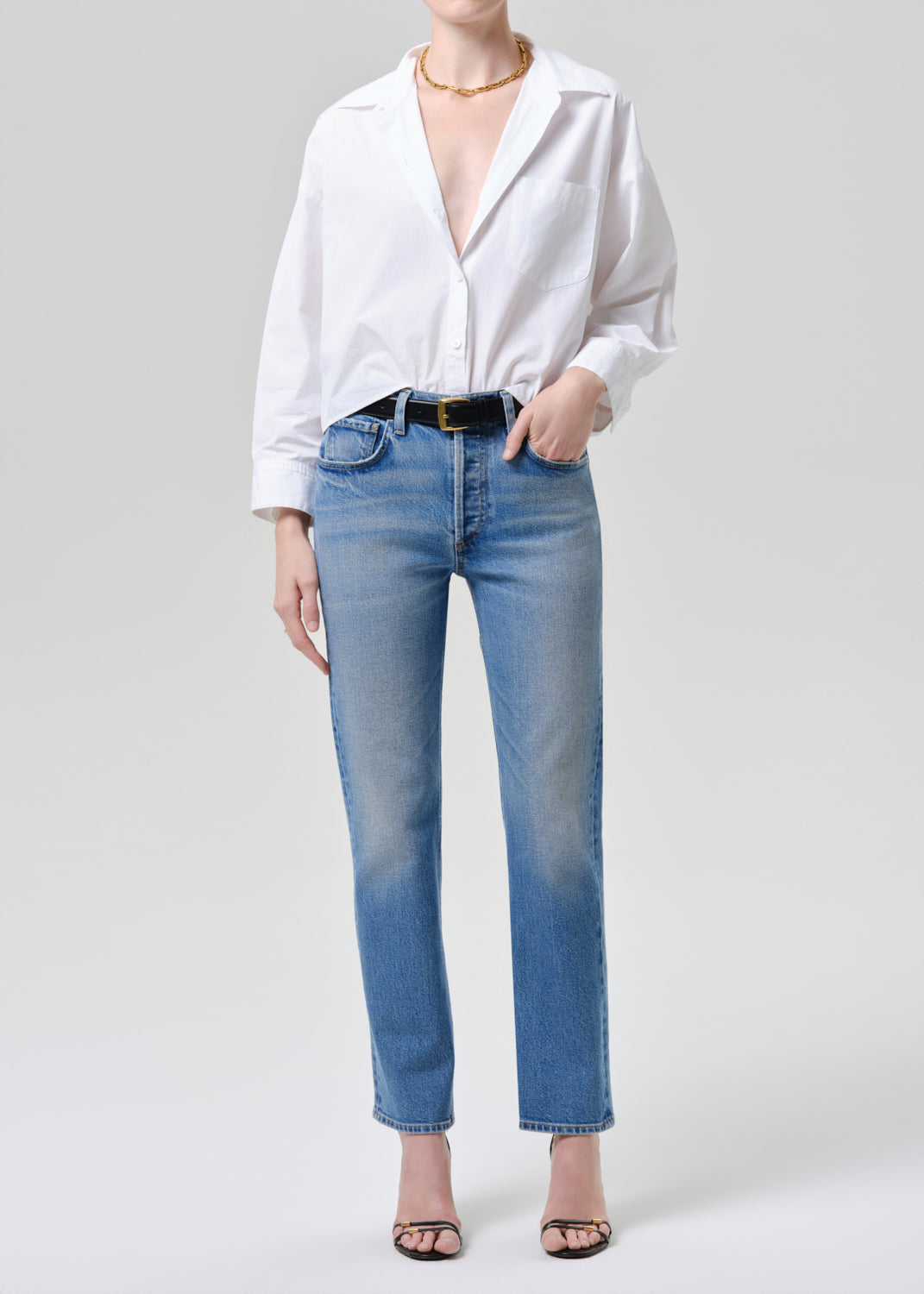 Person wearing a white shirt and blue jeans on a grey background