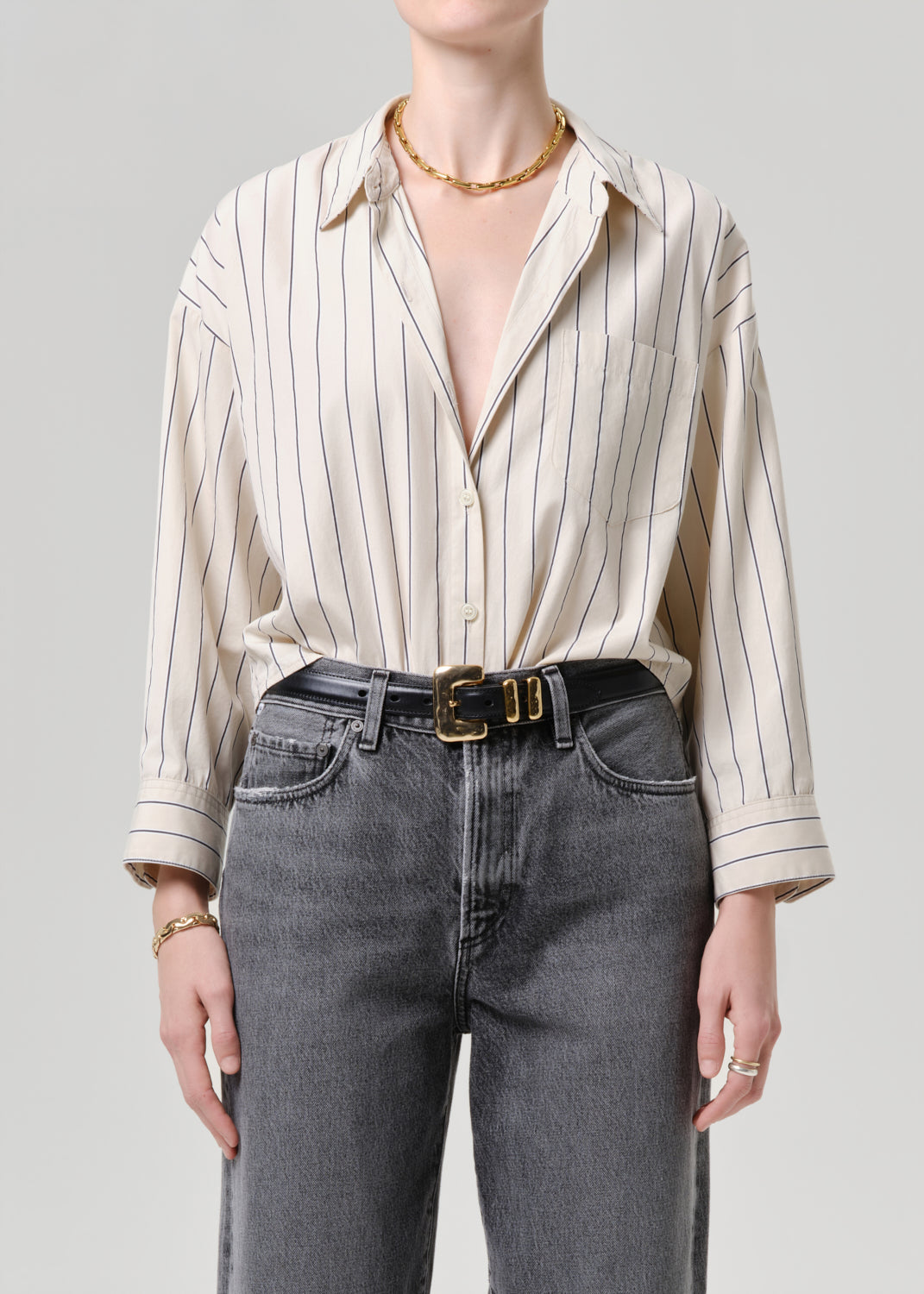 Person wearing a striped shirt and jeans with a grey background