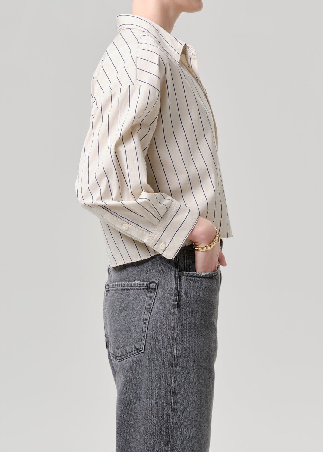 Person wearing a striped shirt and jeans on a grey background