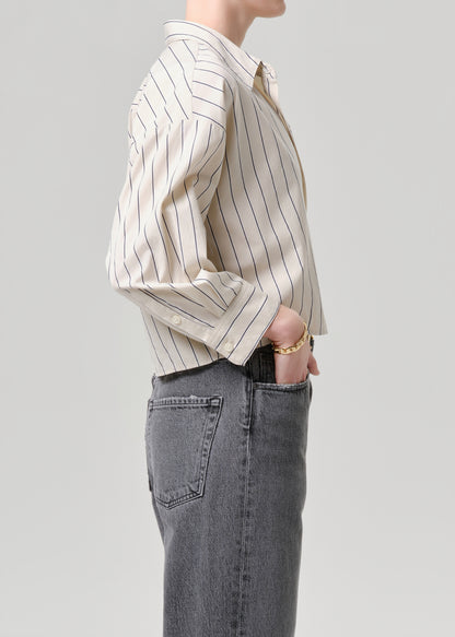 Person wearing a striped shirt and jeans on a grey background