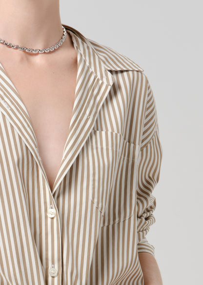 Person wearing a beige and white striped woven shirt on a grey background.