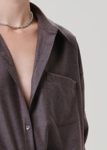 Close-up of a dark brown short sleeve button-up shirt on a grey background.