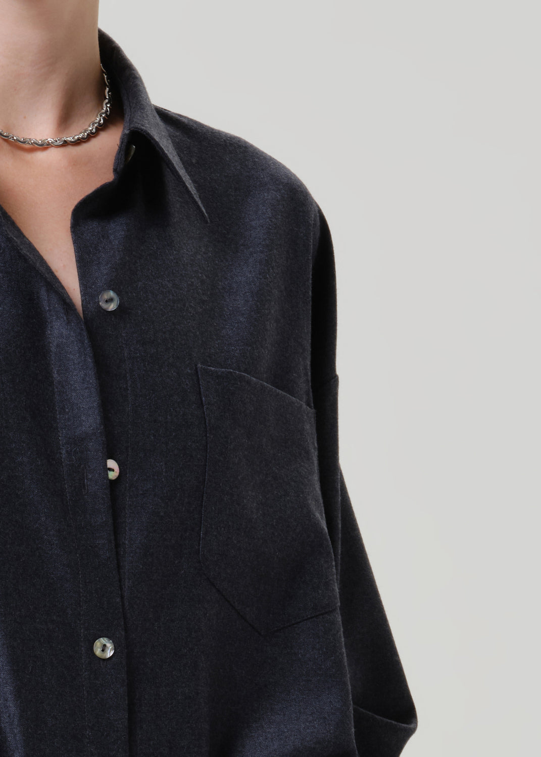 Close-up of a dark navy button-up shirt on a grey background.