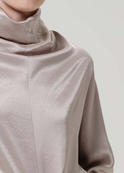 Close-up of a taupe satin draped neck top on a grey background.