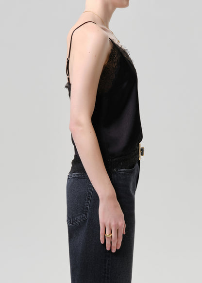 Person wearing a black sleeveless top and dark jeans on a grey background