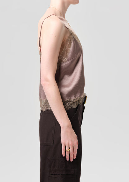 Person wearing a brown lace-trimmed top and dark pants on a grey background