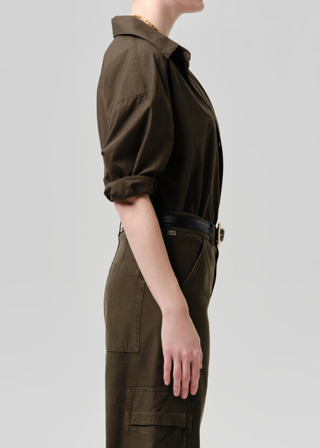 Person wearing a brown jumpsuit on a grey background