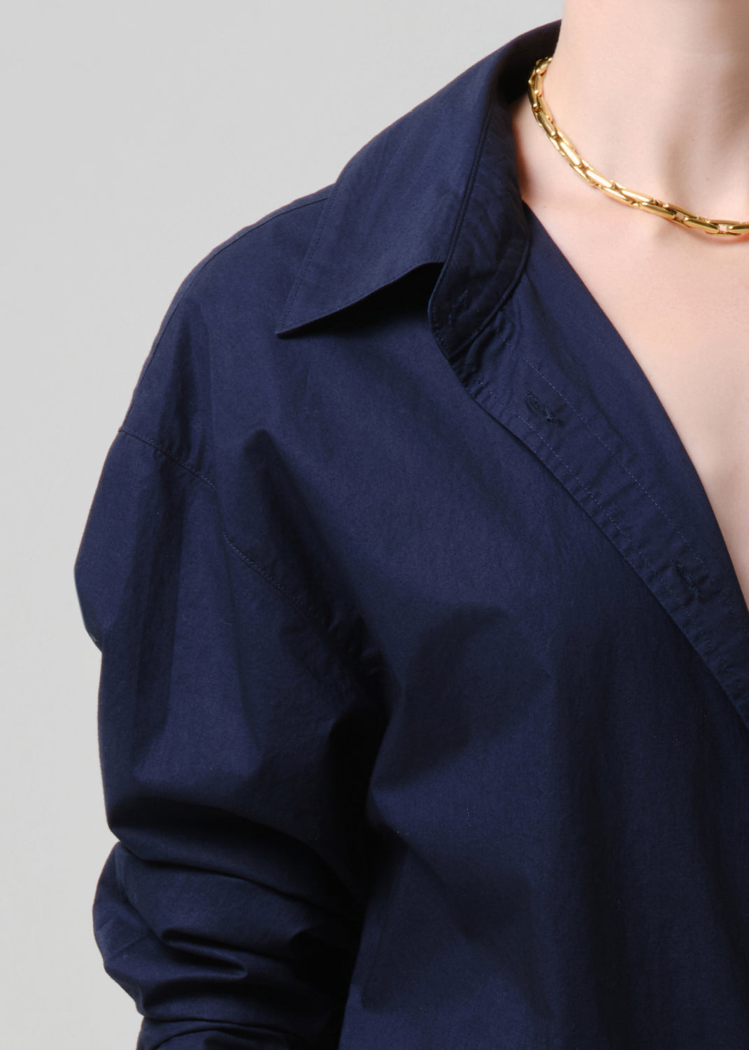 Navy blue shirt worn by a person on a grey background