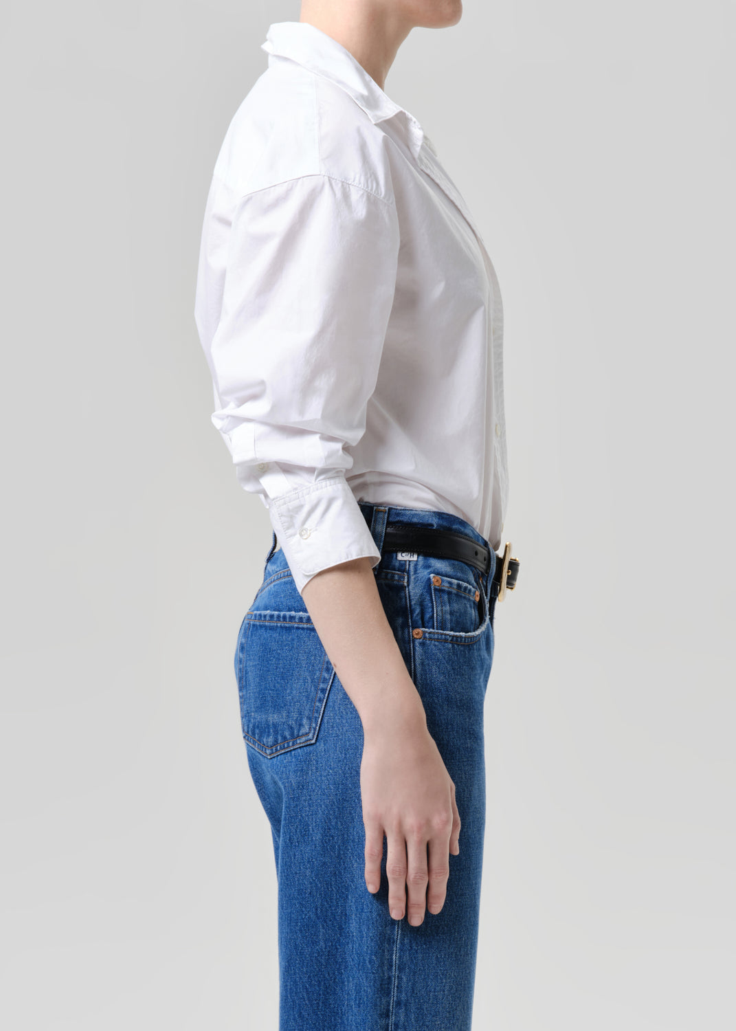 Person wearing a white shirt and blue jeans on a grey background