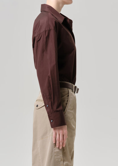 Person wearing a brown shirt and beige pants on a grey background