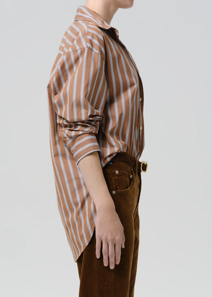Person wearing a brown and white striped shirt with brown pants on a grey  background