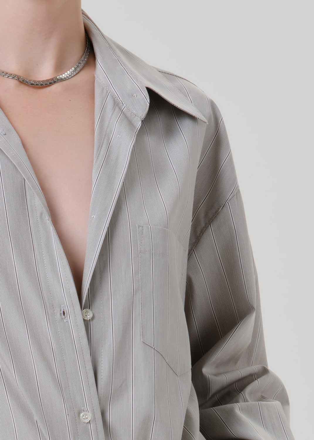 Close-up of a light grey striped button front blouse on a grey background