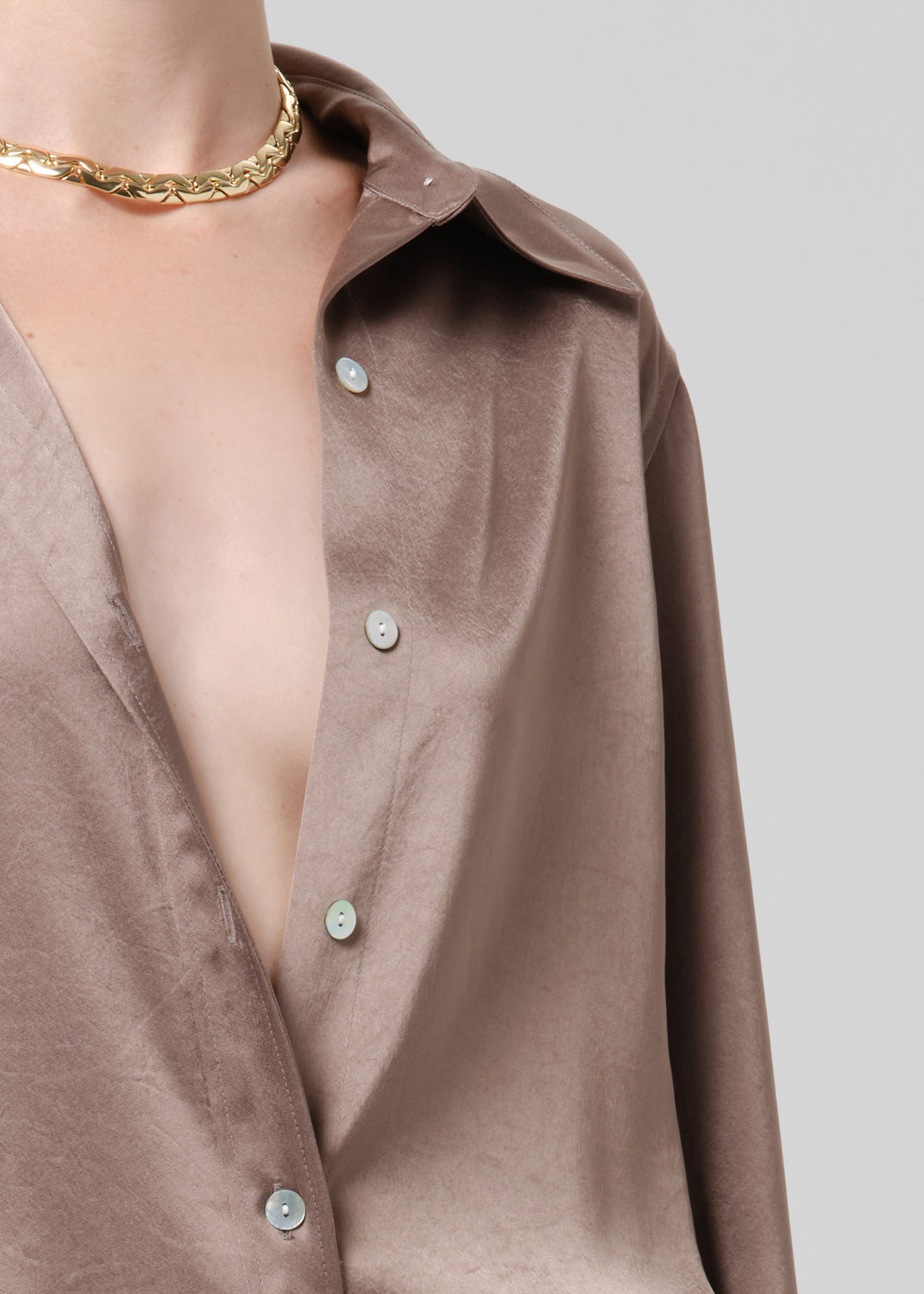 Close-up of a taupe satin button front blouse on a grey background