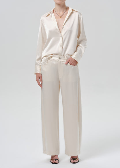 Person wearing an ivory satin button front blouse with ivory wide leg trousers on a grey background