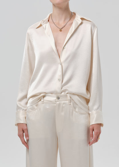 Person wearing an ivory satin button front blouse on a grey background
