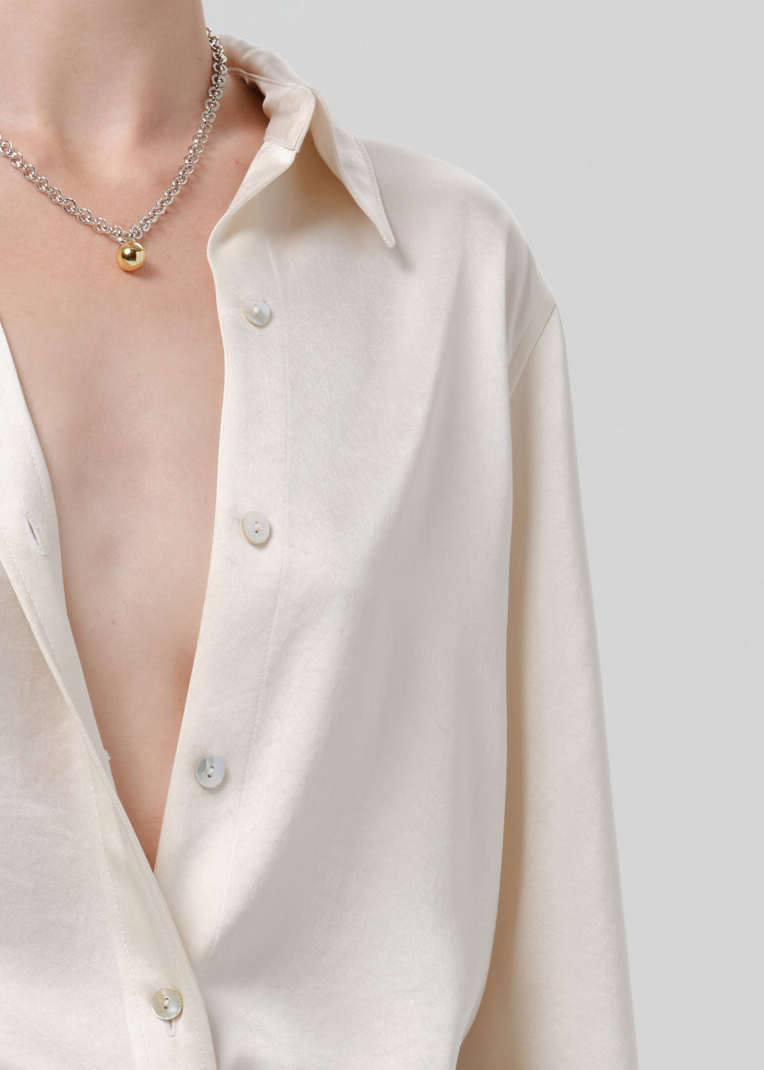 Close-up of an ivory satin button front blouse on a grey background