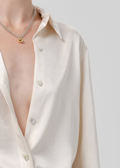 Close-up of an ivory satin button front blouse on a grey background