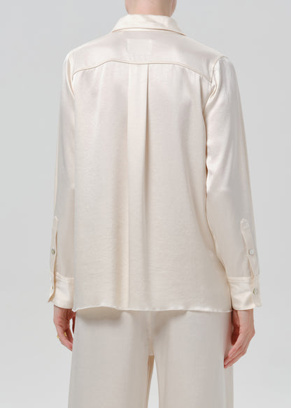 Person wearing an ivory satin button front blouse with ivory wide leg trousers viewed from the back on a grey background