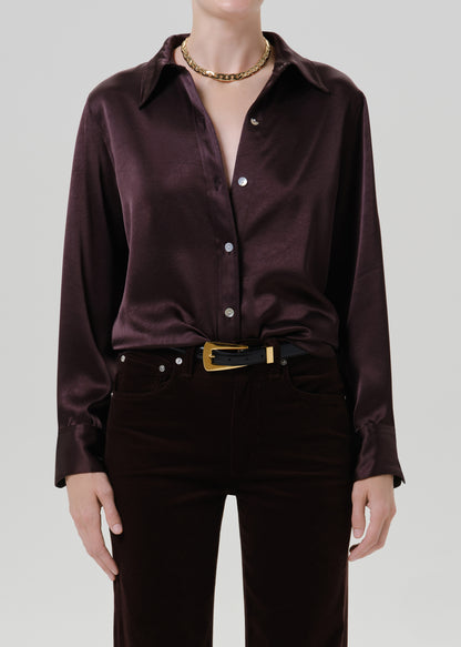 Person wearing a dark brown satin button front blouse on a grey background