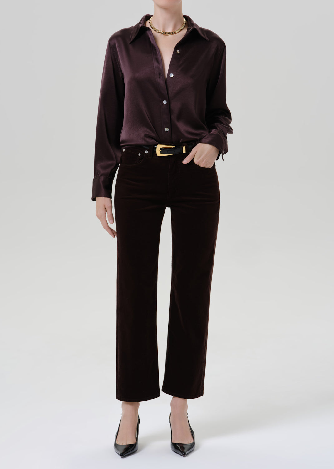 Person wearing a dark brown satin button front blouse with dark brown straight leg pants on a grey background