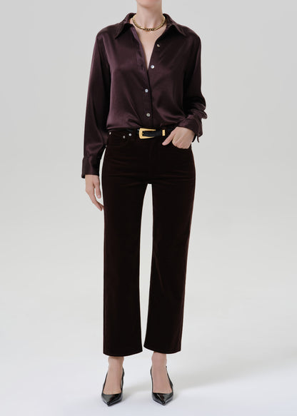 Person wearing a dark brown satin button front blouse with dark brown straight leg pants on a grey background