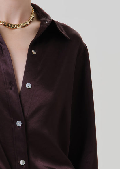 Close-up of a dark brown satin button front blouse on a grey background