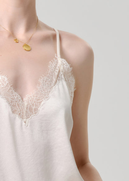 White lace-trimmed slip dress worn by a model on a grey background