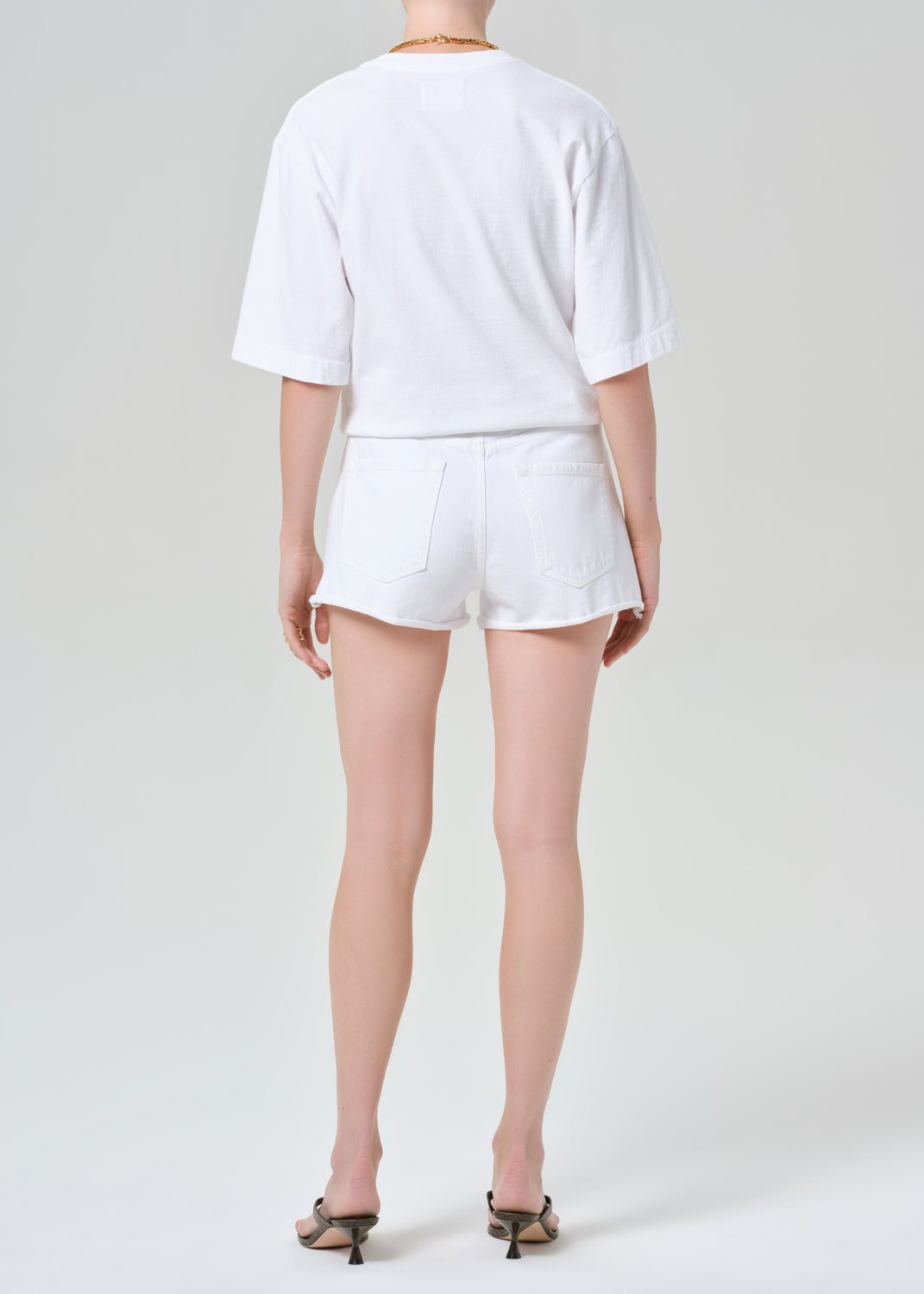 Person wearing a white t-shirt and shorts on a plain background