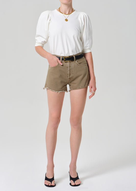Person wearing a white top and brown shorts on a plain background