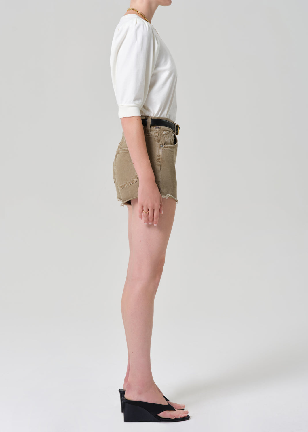 Person wearing a white top and brown shorts on a plain background
