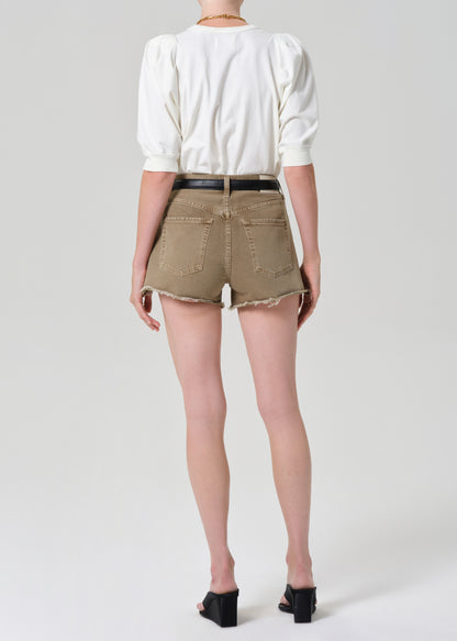 Person wearing a white top and brown shorts on a plain background