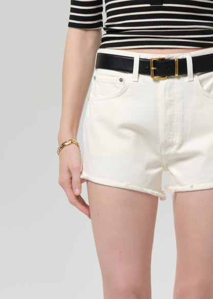 Person wearing a black and white striped shirt with white shorts and a black belt on a light gray background