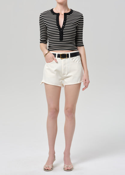 Person wearing a black and white striped crop top and white shorts on a plain background