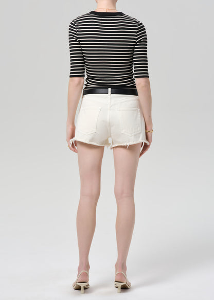 Person wearing a black and white striped shirt with a belt and white shorts on a white background