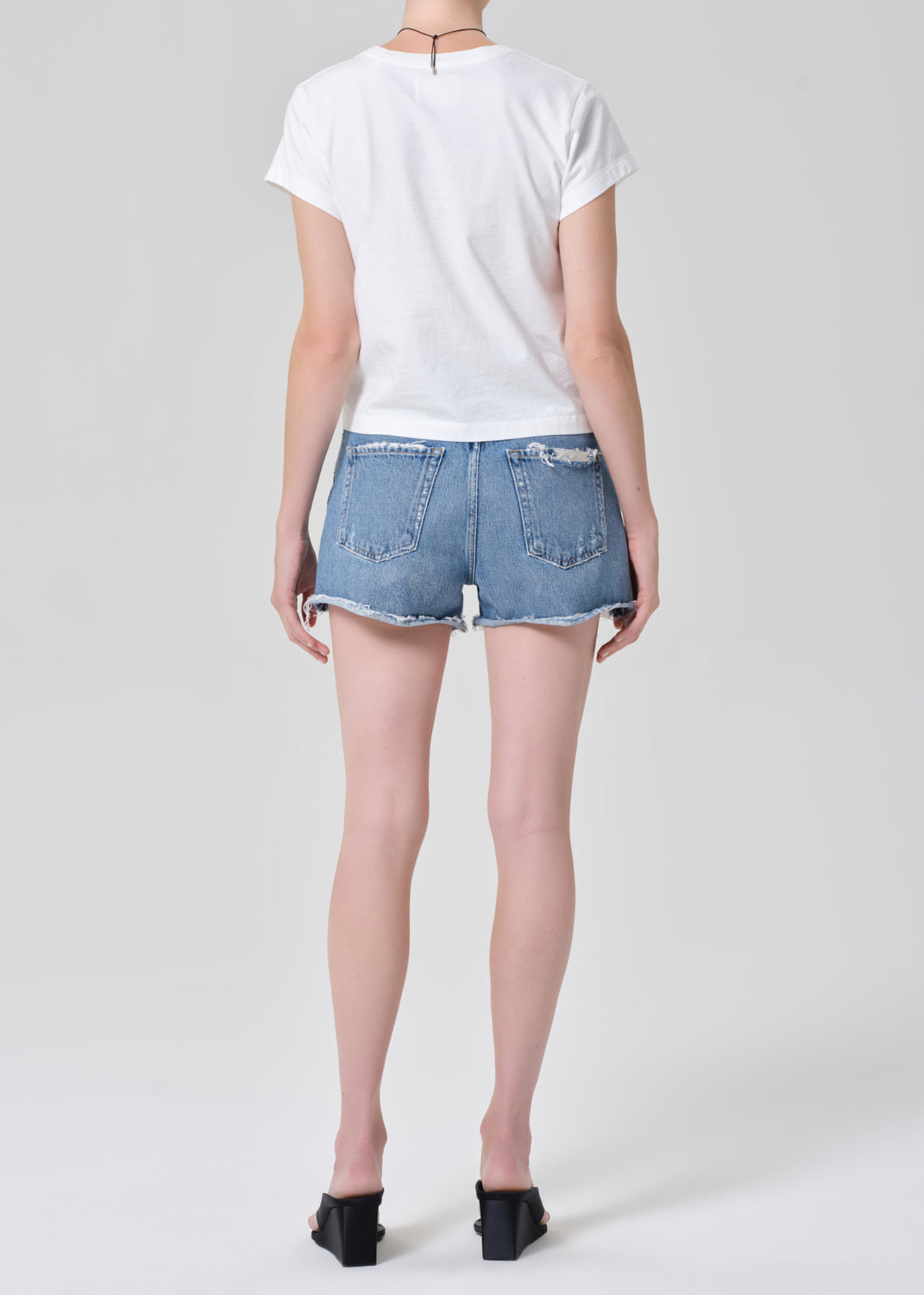 Person wearing a white t-shirt and denim shorts on a plain background