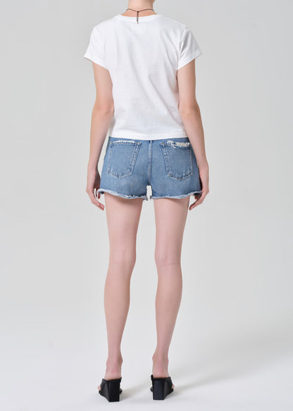 Person wearing a white t-shirt and denim shorts on a plain background