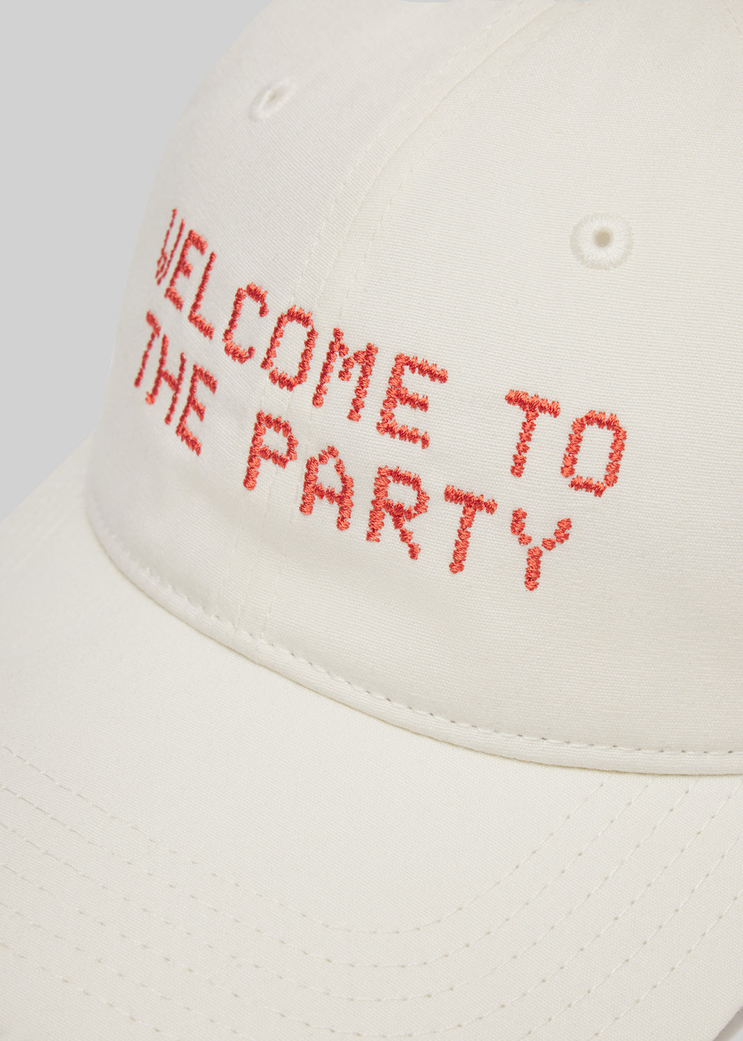 Cream cap with 'Welcome to the Party' text in red on a white background