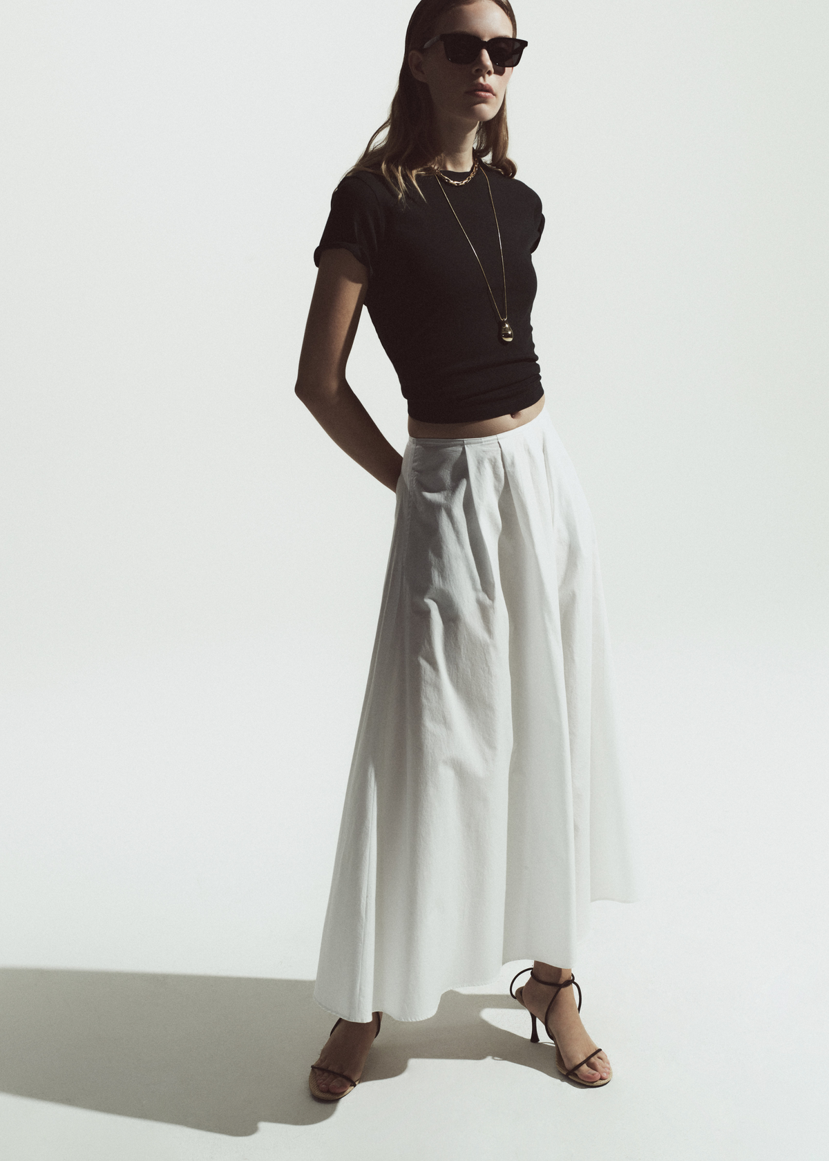 Person wearing a black tee with white poplin skirt