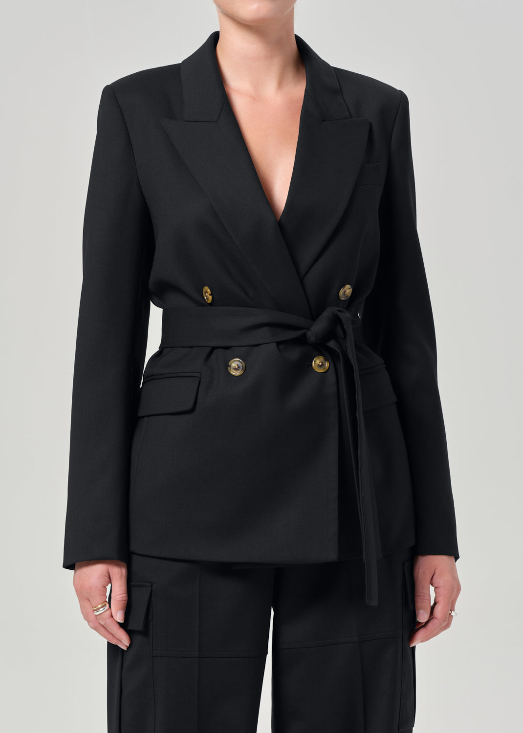 Black blazer with gold buttons on a plain background