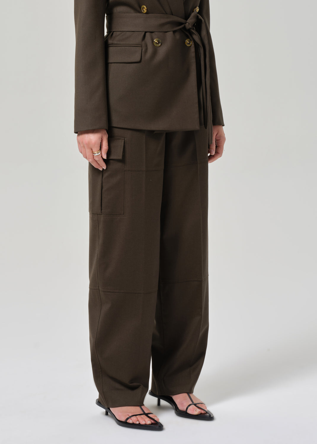 Person wearing a brown suit with wide-leg pants on a grey background