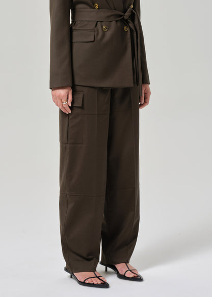 Person wearing a brown suit with wide-leg pants on a grey background