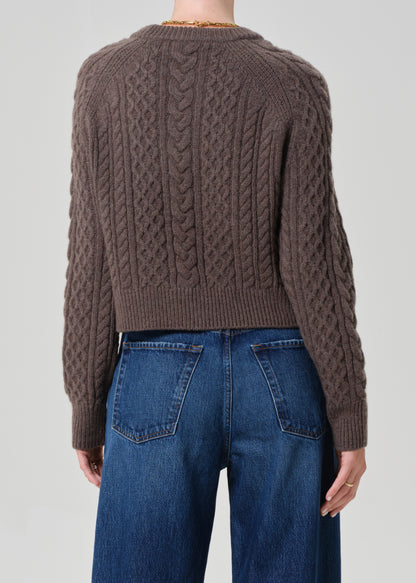 Brown cable knit sweater worn by a person on a plain background