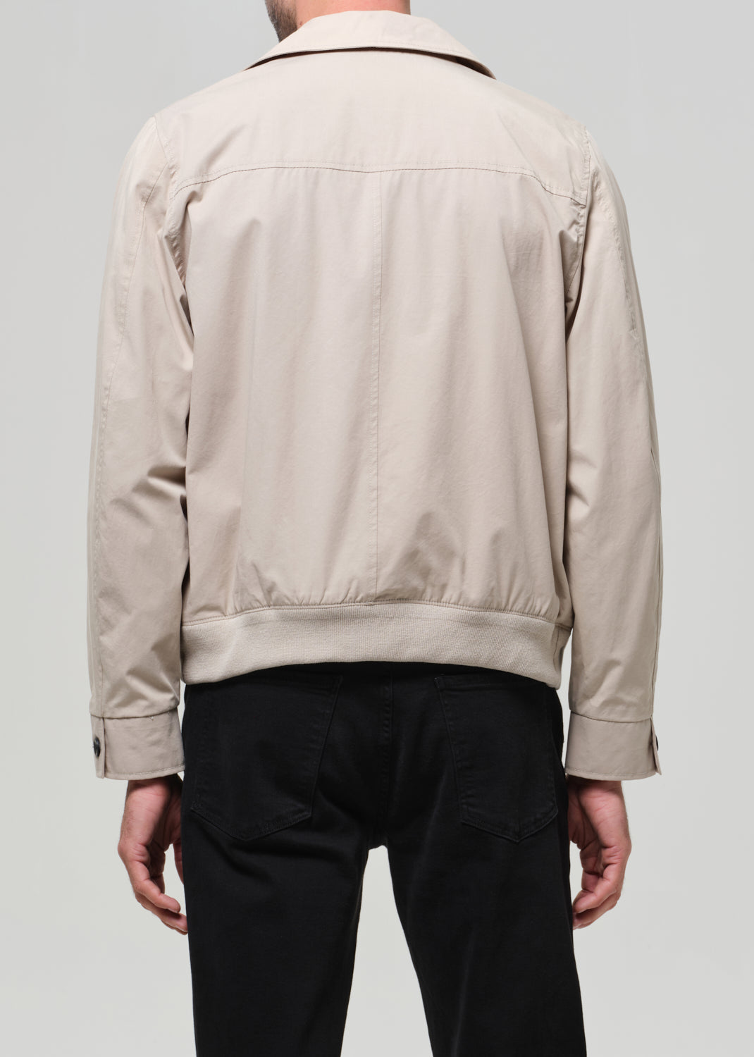 Beige jacket worn by a person on a plain background