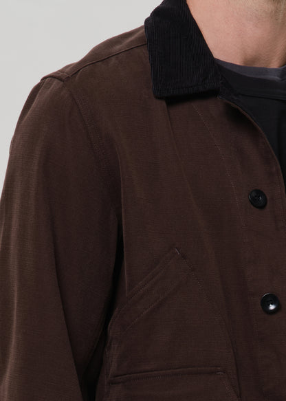 Close up shot of man wearing a dark brown corduroy jacket over a black shirt.