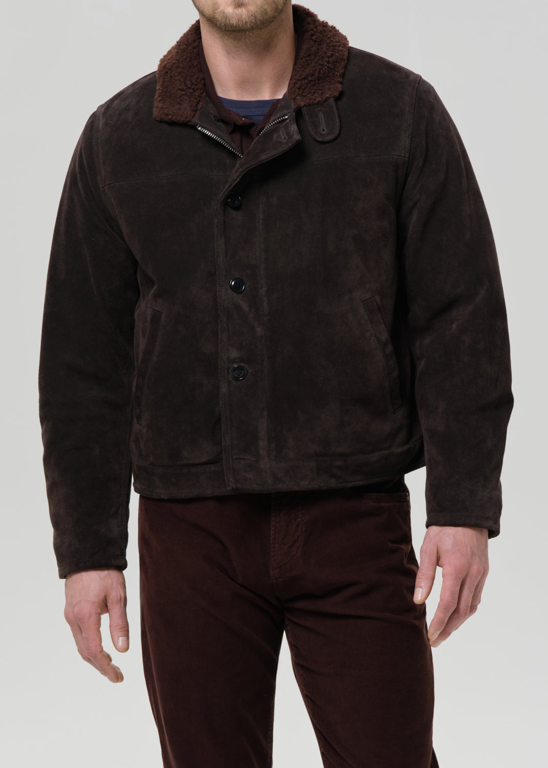 Man wearing a brown jacket with a fur collar on a grey background