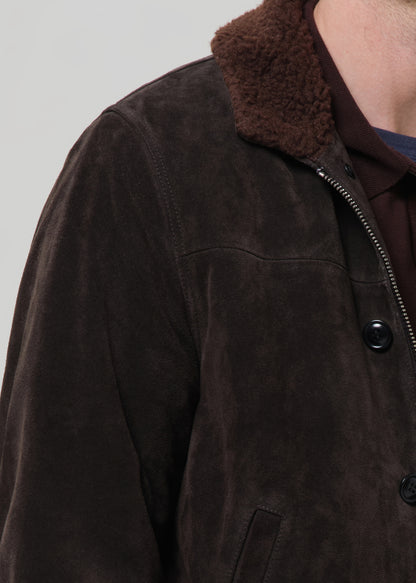 Close-up of a brown jacket with a fur-lined collar on a grey background