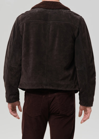 Brown suede jacket worn by a person on a grey background