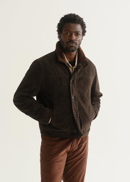 Person wearing a dark brown jacket over a dark shirt with rust brown pants, front cropped view on a light grey background.