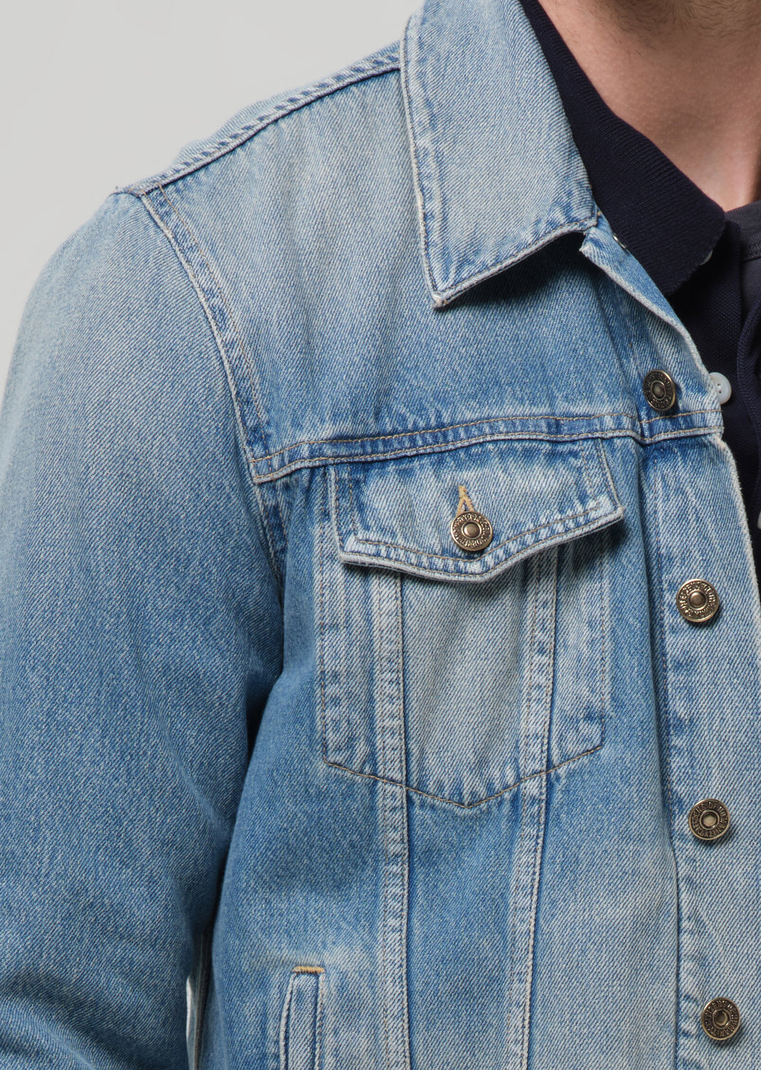 Close-up of a blue denim jacket with buttons on a grey background