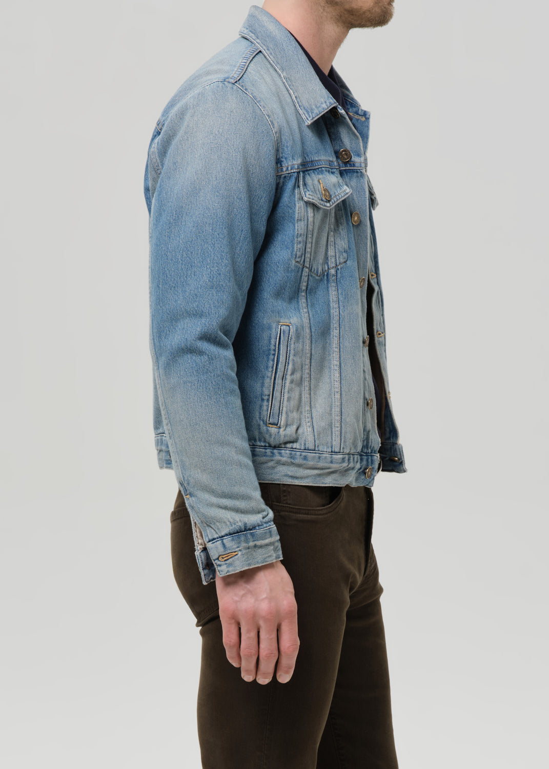 Person wearing a light blue denim jacket on a grey background